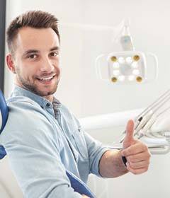 man in the dental chair giving a thumbs up 