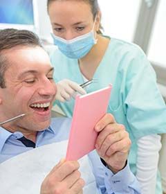 man admiring his reflection after getting dental implants