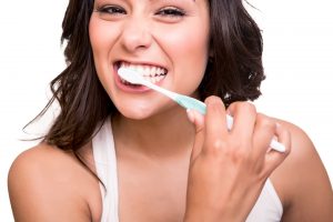 woman smiling while brushing teeth