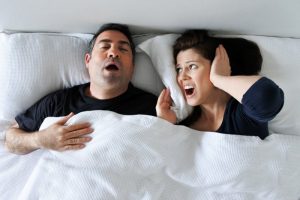 a man snoring and his wife covering her ears