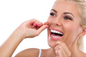 Woman flossing her teeth at dentist in Freedom. 