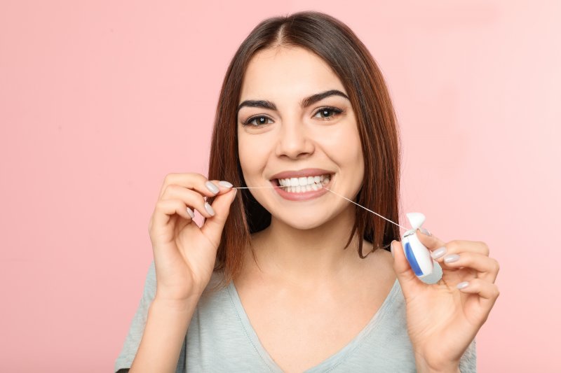 Woman smiling while flossing her teeth