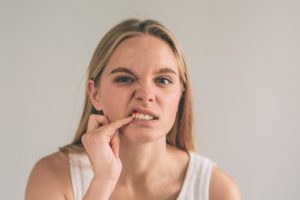 Woman concerned about gum disease poking at her gums