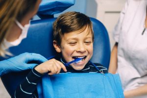 young boy brushing his teeth while visiting his children’s dentist in Freedom 