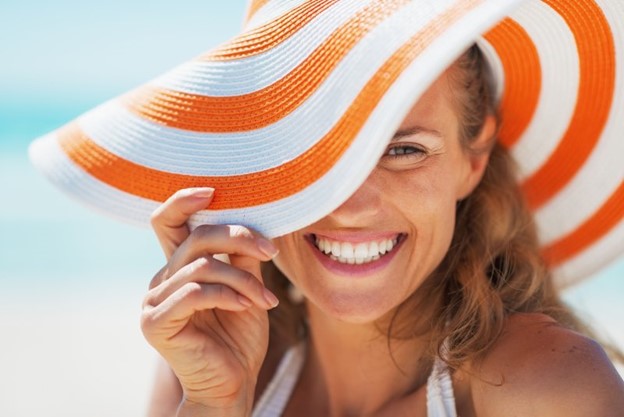 Woman smiling at the beach after receiving porcelain veneers.