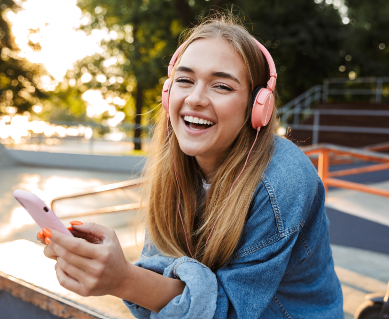 Teen on phone, smiling, with headphones on